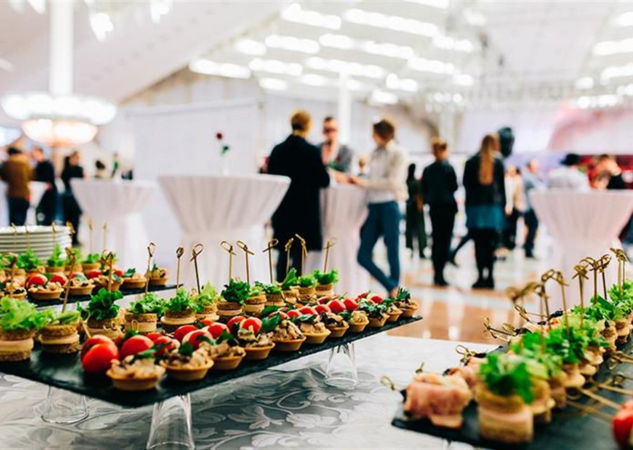 Appetisers and canapés on an event buffet with guests in the background